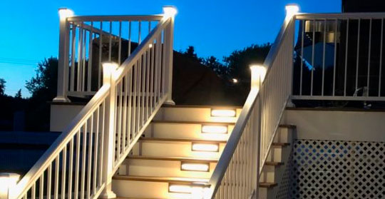 White vinyl railing along a deck staircase with illuminated steps